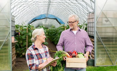 senior couple with box of vegetables on farm