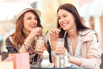 Two beautiful young girls sitting in a cafe