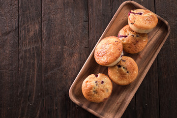 Blueberry muffins with fresh berries on old wooden background