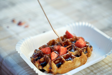 waffle with strawberry on paper plate and fork