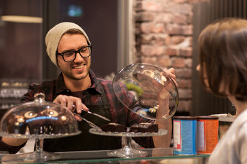 man or barman with cakes serving customer at cafe