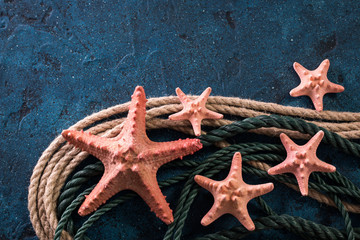 Summer time sea vacation background with star fish, marine rope on dark blue background