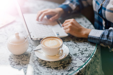 Close-up of hands of woman working in cafe table. Intentional sun glare