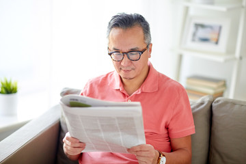 happy man in glasses reading newspaper at home