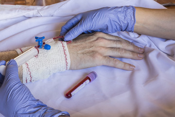 Doctor blood drawn with a syringe holding the arm of a man in hospital