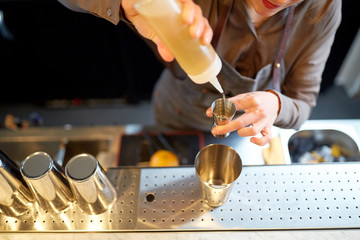 bartender with cocktail shaker and jigger at bar