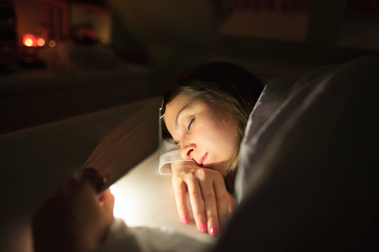 Pretty young woman fall asleep during reading on book reader / ebook, sleeping