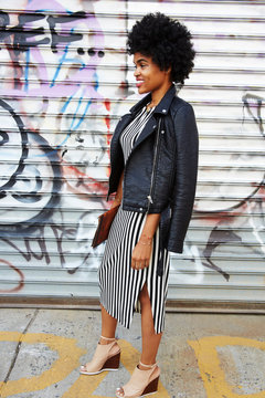 Young female fashion blogger with afro hair by graffiti wall, New York, USA