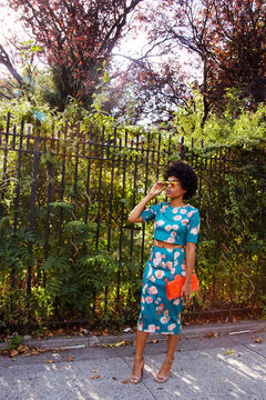 Young female fashion blogger with afro hair waiting on park sidewalk, New York, USA