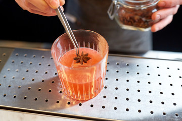 bartender with glass of cocktail and anise at bar
