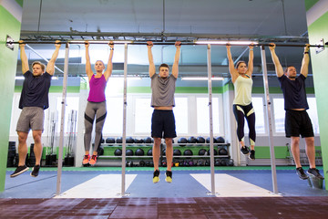 group of people hanging at horizontal bar in gym