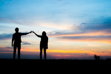 Silhouette of couple hands in love at sunset.