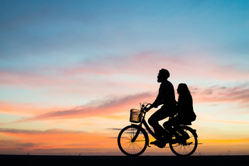 Obraz na płótnie Canvas Silhouette couple and bycicle on sunset.