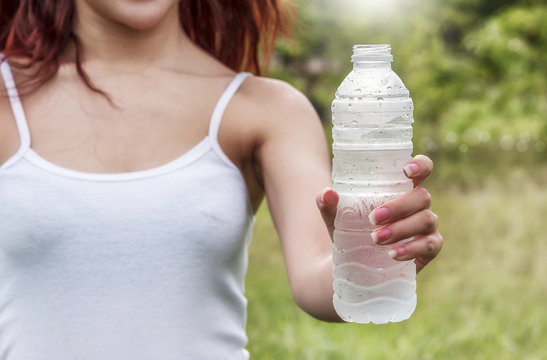Young woman in white tank top  show bottle of water