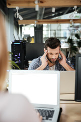 Concentrated thinking man in office coworking while using laptop