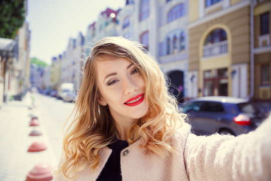 Selphi photo of a young girl on the background of a sunny old city street