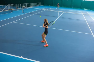 Foto op Canvas The young girl in a closed tennis court with ball © master1305