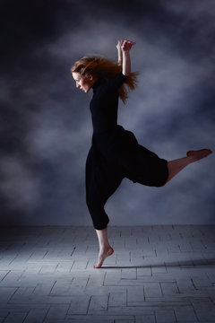 Modern ballet dancer posing on dark background