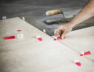 Ceramic Tiles. Tiler placing ceramic tile in position over adhesive with lash tile leveling system