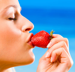 Young woman with strawberry on beach