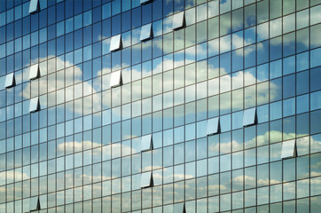 Fototapeta na wymiar Modern glass office building with clouds and sky reflections