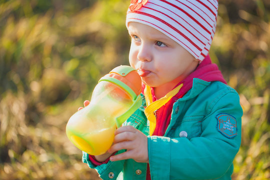 Little Girl Drinks Juice From A Bottle