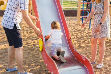 summer, childhood, leisure and family concept - happy child and his parents on children playground climbing frame