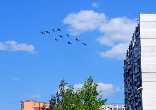     Группа из многофункциональных истребителей-бомбардировщиков Су-34, многоцелевых всепогодных истребителей Су-27 и многоцелевых сверхманёвренных истребителей Су-35с в небе над жилыми домами 