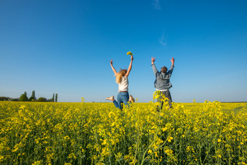 Man with a young beautiful woman are jumping and having fun in a field