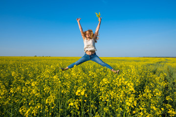 Joyful young woman, blonde jumping and having fun in a field