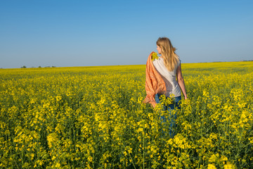 Fototapeta premium Beautiful young woman, blonde with flying hair is walking through a field