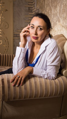 Business woman dressed into pants, white blouse and tie posing in a rich interior