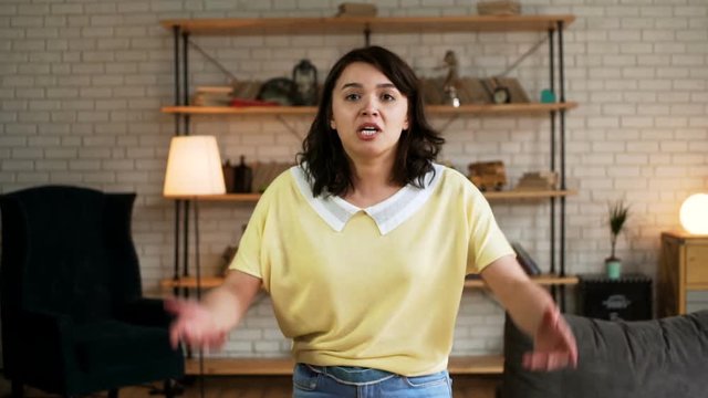 Young dark haired furious unhappy woman quarrel emotionally and shout at the camera, because of broken heart
