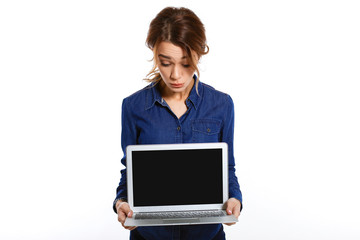 Look here! Attractive young woman in blue shirt looking at laptop, standing on white background