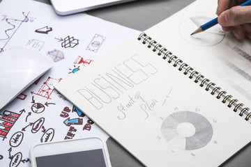 Creative sketch in spiral notepad with laptop on desk. Business startup plan.