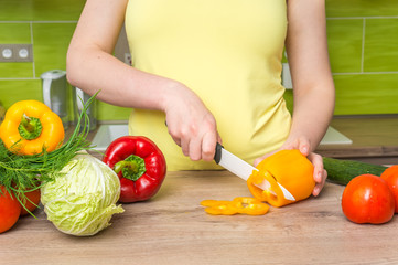 Woman cutting peppers for salad - fresh vegetables concept