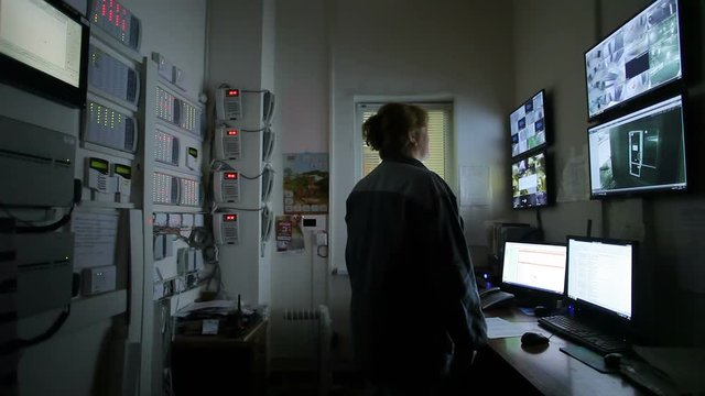 Female operator Looking At Multiple Camera Footage On Computers
