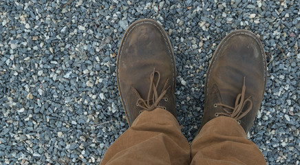 Male feet in leather brown shoes and mustard trousers