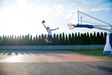 Young man jumping and making a fantastic slam dunk playing stree © FS-Stock