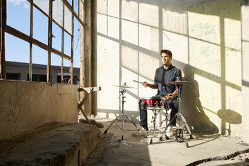 Young musician. Shot of a young drummer sitting at his drum set and playing music.