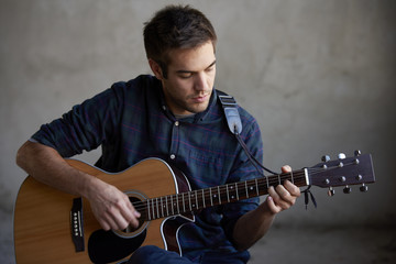Obraz premium Young talent. Close-up shot of a young musician playing his acoustic guitar.