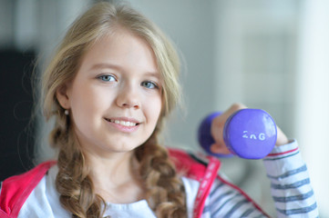 Teenage girl in the gym with dumbbells