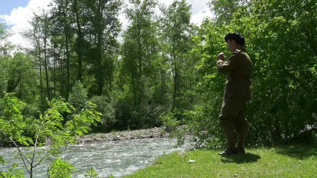 man with old french military uniform, smoking cigarette near the river