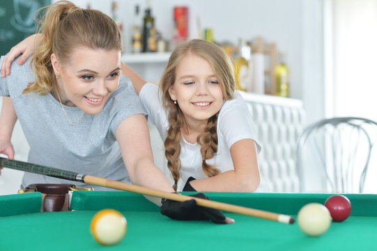 Mother with her daughter playing pool