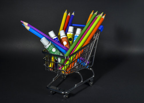 shopping cart full with artistic goods for drawing on black background.
