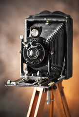Old camera on a tripod on an old background close-up