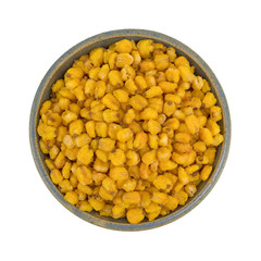 Top view of toasted corn nuts in an old stoneware bowl isolated on a white background.
