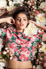 Portrait of beautiful sensual woman lying down on flowers in studio photo. Beauty concept. Floral decoration