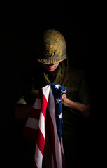 Distraught US marine (Vietnam War) holding the American flag.