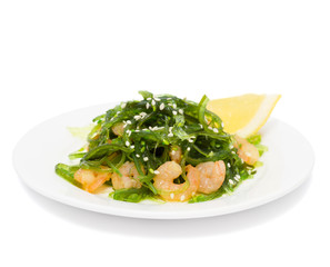 Salad of seaweed (chuka) with prawns under soy sauce and sesame oil is decorated with sesame seeds and lemon, isolated on white